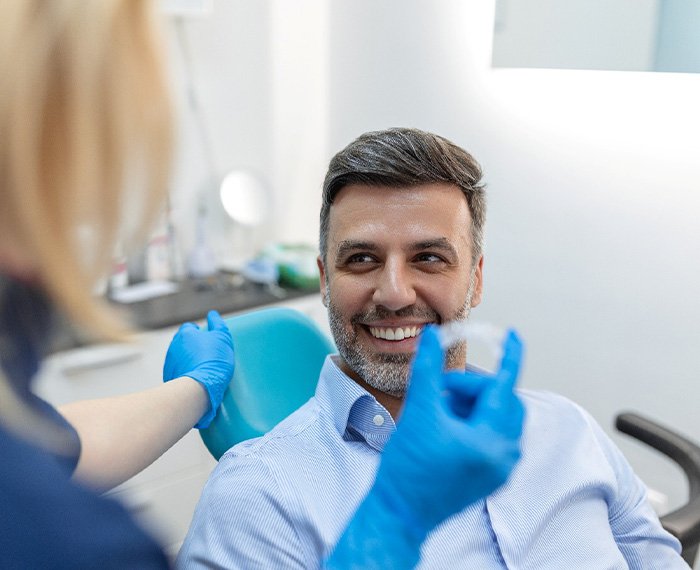 Patient smiling at dentist holding clear aligner