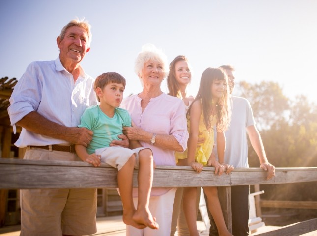 Three generations of smiling family on wooden bridge