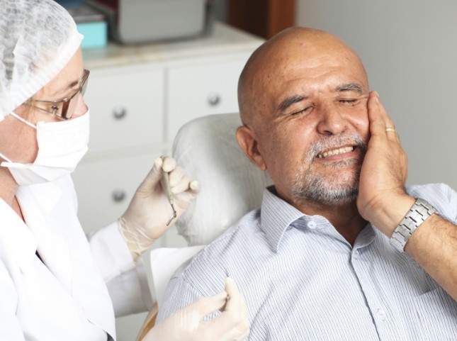 Senior dental patient holding his cheek in pain