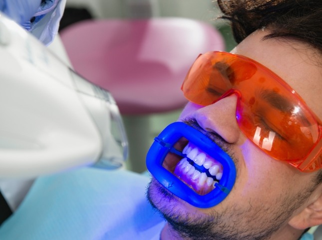 Man getting his teeth professionally whitened in dental office