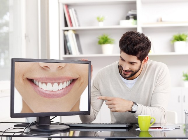 Man pointing to computer monitor showing a flawless smile