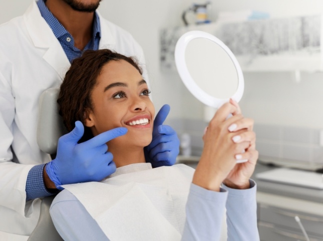 Dental patient admiring her new smile in a mirror
