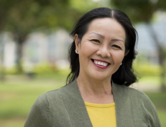 Woman in dark green jacket smiling outdoors