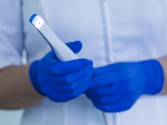 Dental professional holding a thin white intraoral camera