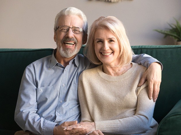 Man and woman on green couch smiling