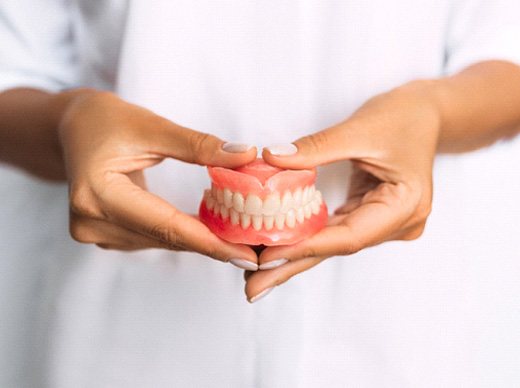 Pair of hands holding full set of dentures