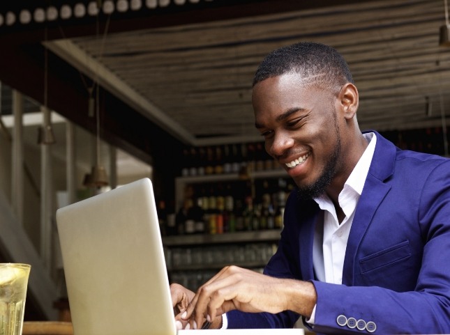 Man smiling while typing on laptop