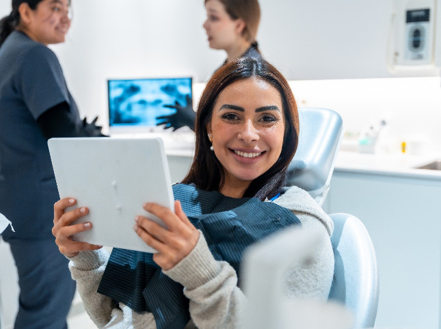 Patient smiling while holding mirror in treatment chair