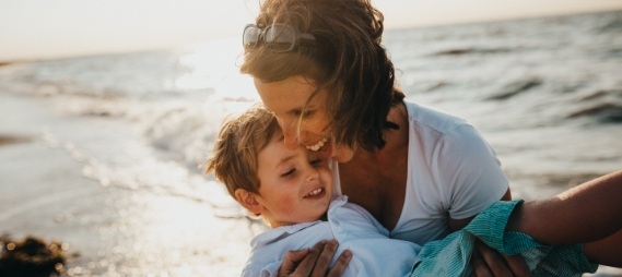 Mother laughing with her young son on the beach