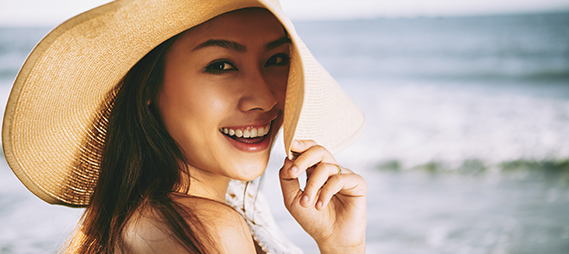 Woman in sunhat smiling on the beach