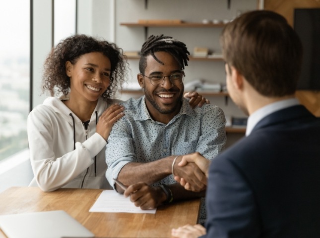 Smiling man shaking hands with person across desk