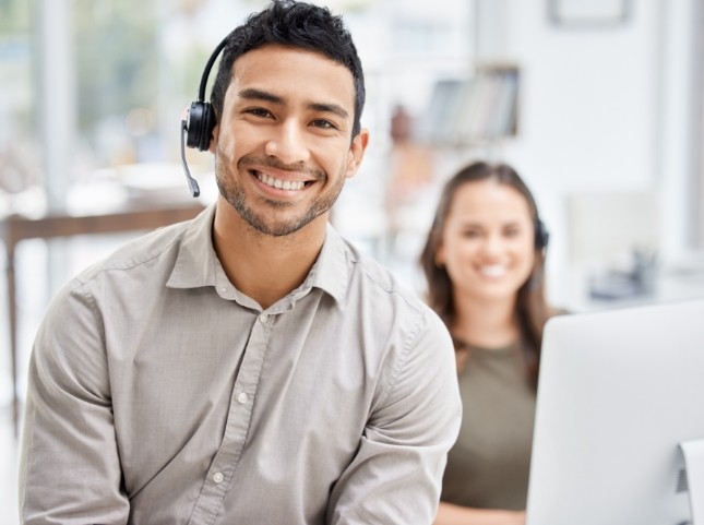 Smiling man sitting in an office wearing a phone headset