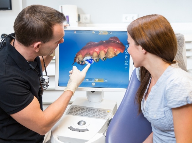 Dentist showing a patient a model of their teeth on computer monitor