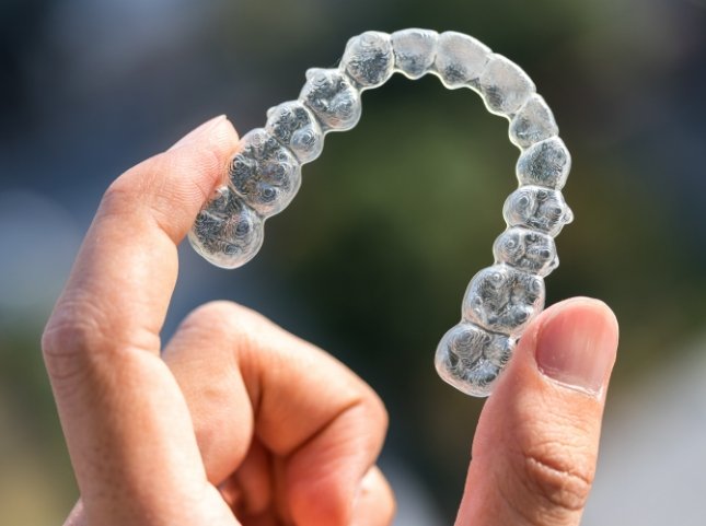 Hand holding an Invisalign clear aligner