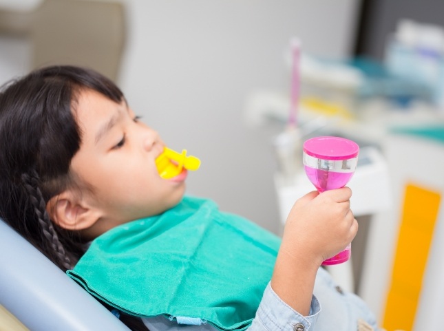 Young girl in dental chair with fluoride trays on her teeth