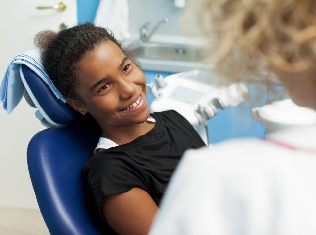 Girl in dental chair smiling at her dentist