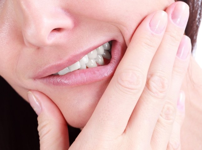 Person holding their mouth in pain before tooth extractions in San Ramon