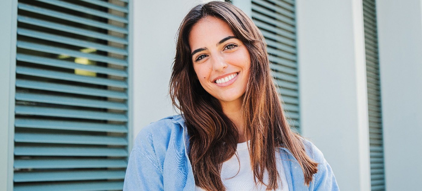 Woman with white teeth smiling while standing outside