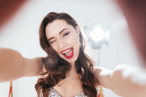 Woman in a spotlight grabbing the camera and smiling